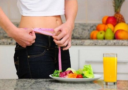 Une fille qui perd du poids pendant un régime mesure son tour de taille
